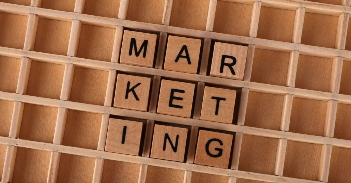 Wooden letter tiles spell out the word marketing on a grid background, showcasing creativity and business concept.